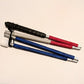 A folded blind cane, covered in rhinestones that  are ruby red at the top, silvery white in the middle, and blue towards the bottom.