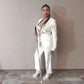 Lachi, a black woman with cornrows, poses with a gold and white glam cane and an all white pantsuit