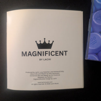 A square white product box with the brand name 'MAGNIFICENT BY LACHI' printed in black, photographed on a dark textured surface.