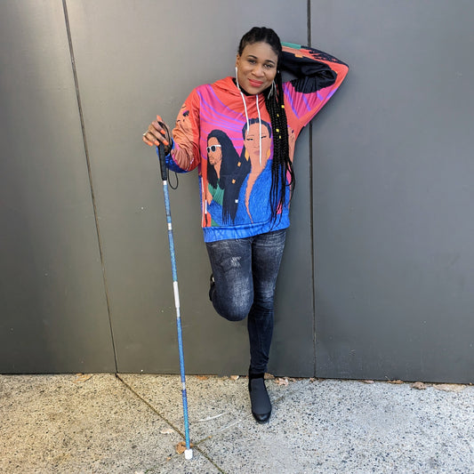 Lachi, a black woman with cornrows, poses wearing a colorful sweater featuring the album art for her single Black Girl Cornrows which has drawn profiles of Lachi and the other artists over an orange background
